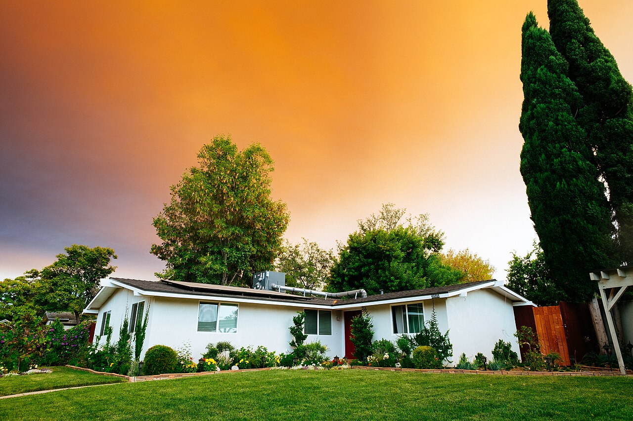Single-story neighborhood home with a front lawn and mature trees
